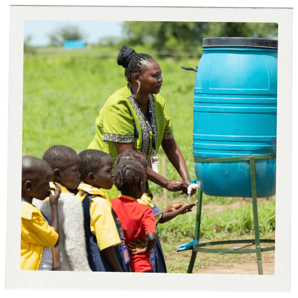 Woman pouring out water from jug for line of children